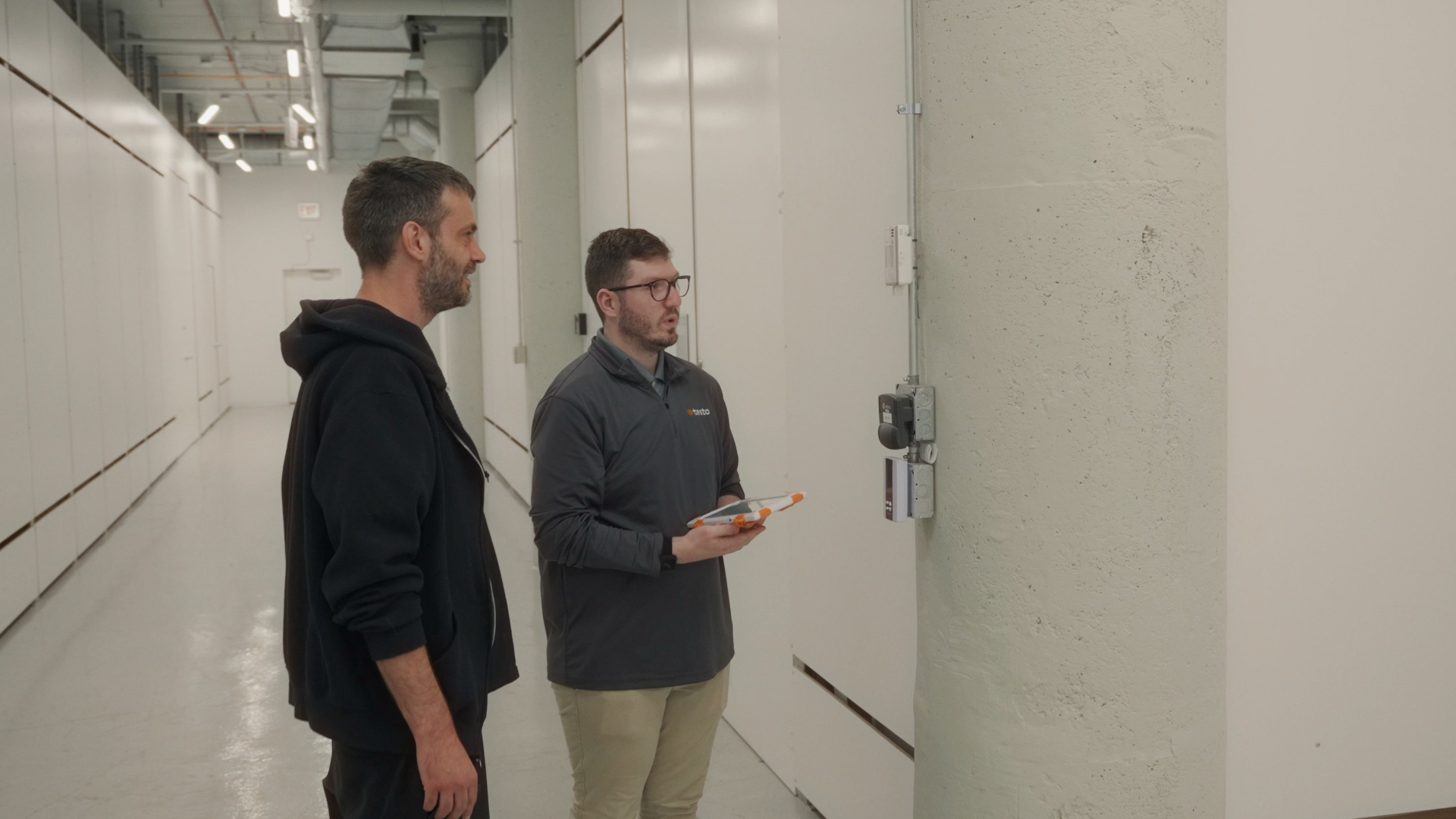 Two people standing in white hallway looking to the right