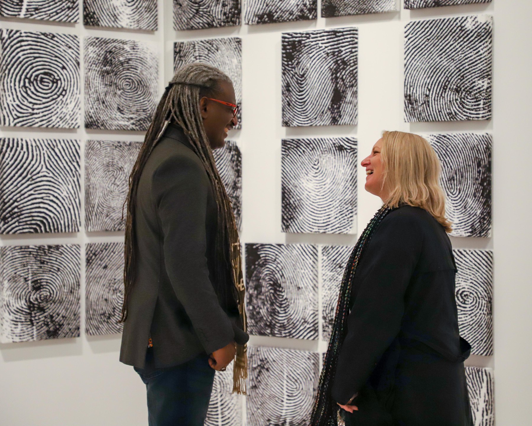Artist Elshafei Dafalla (left) speaks with a visitor in front of his artwork Delirium (2005).